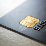 Black credit card with chip and contactless pay technology close-up. Low key shot with old credit card.